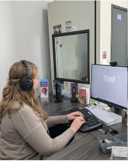 Audiologist performing diagnostic hearing testing in a sound booth